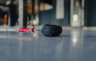 This image shows a needle roller used for applying epoxy paint on a floor.